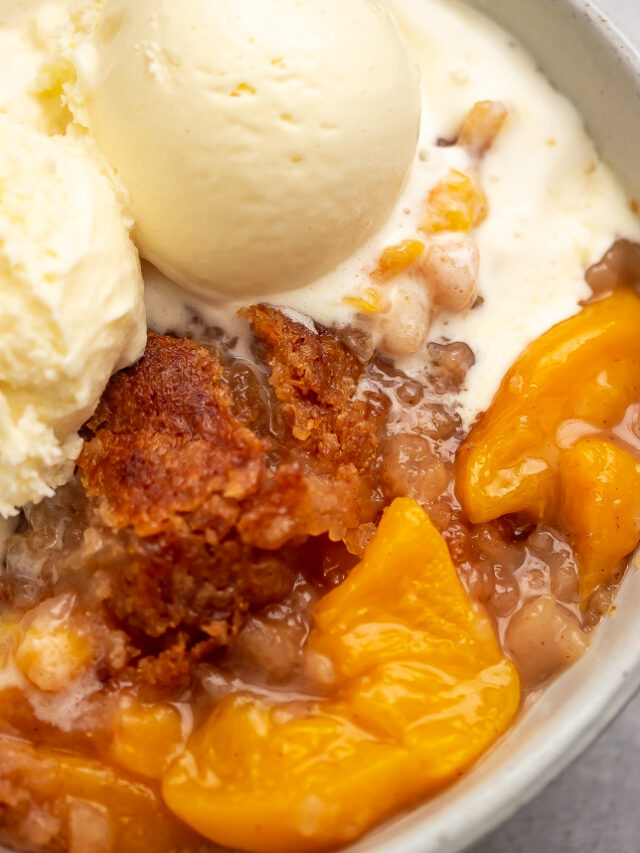 A bowl of ice cream with buttery crisp topping peach cobbler