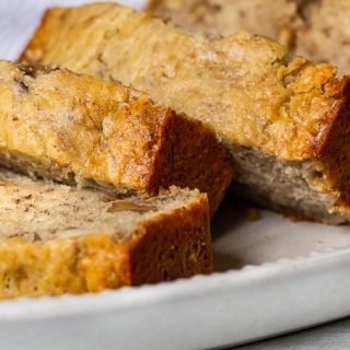 Plate of golden banana bread studded with walnuts on a serving dish