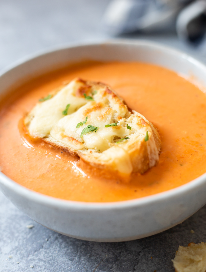 Tomato bisque soup in a bowl topped with cheesy toasted ciabatta 