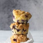 3 old fashioned blueberry muffins stacked on top of one another