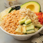 A tuna bowl with pickled cucmbers, carrots brown rice topped with spicy mayonnaise