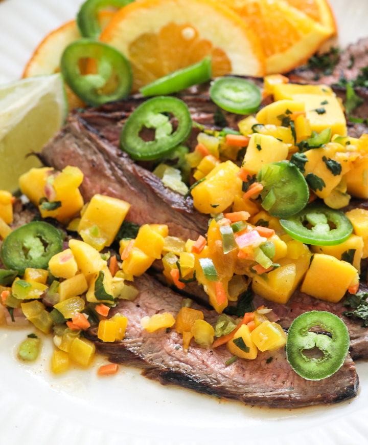 Jerk steak with mango salsa on a white plate with a bottle of mazola heart healthy corn oil behind it