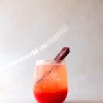 A stemless wine glass of pink strawberry rhubarb soda filled with ice.